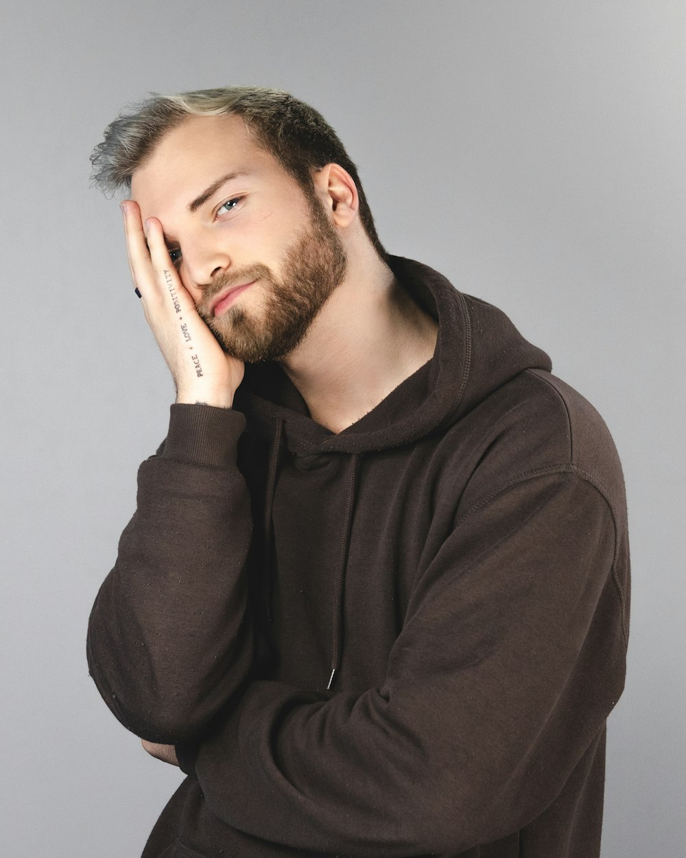 man in brown hoodie covering his face