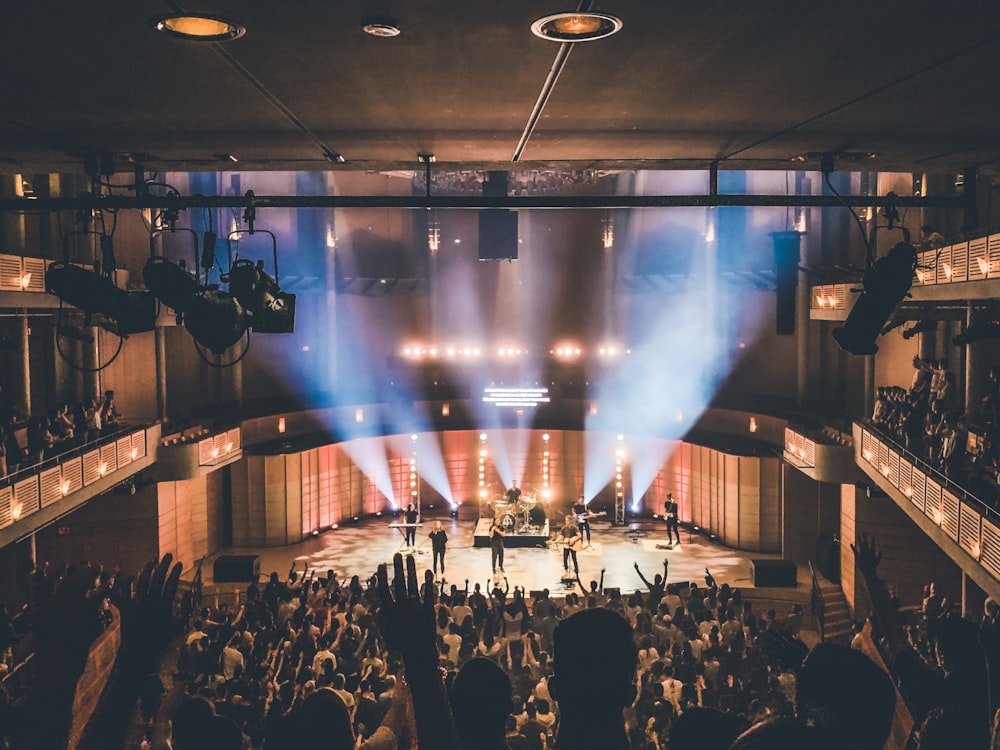 people standing on stage with lights turned on during nighttime