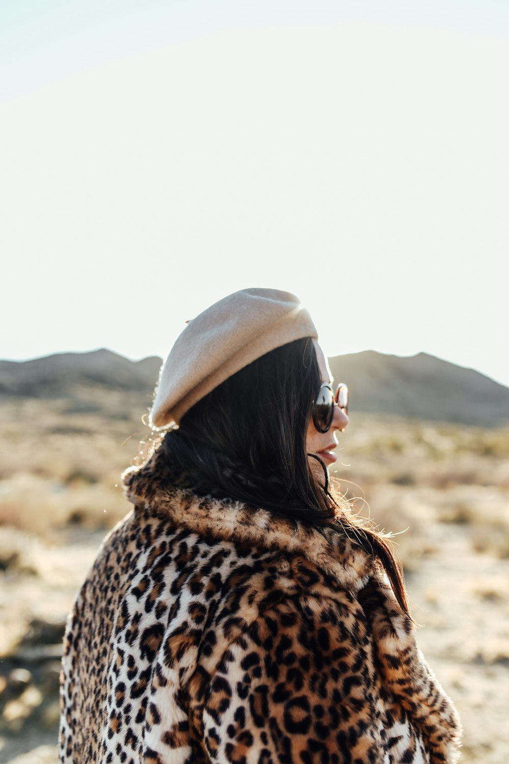 Femme en manteau imprimé léopard marron et noir portant des lunettes de soleil noires