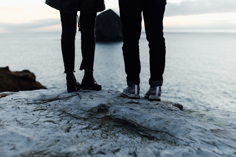 person in black pants and black shoes standing on gray rock