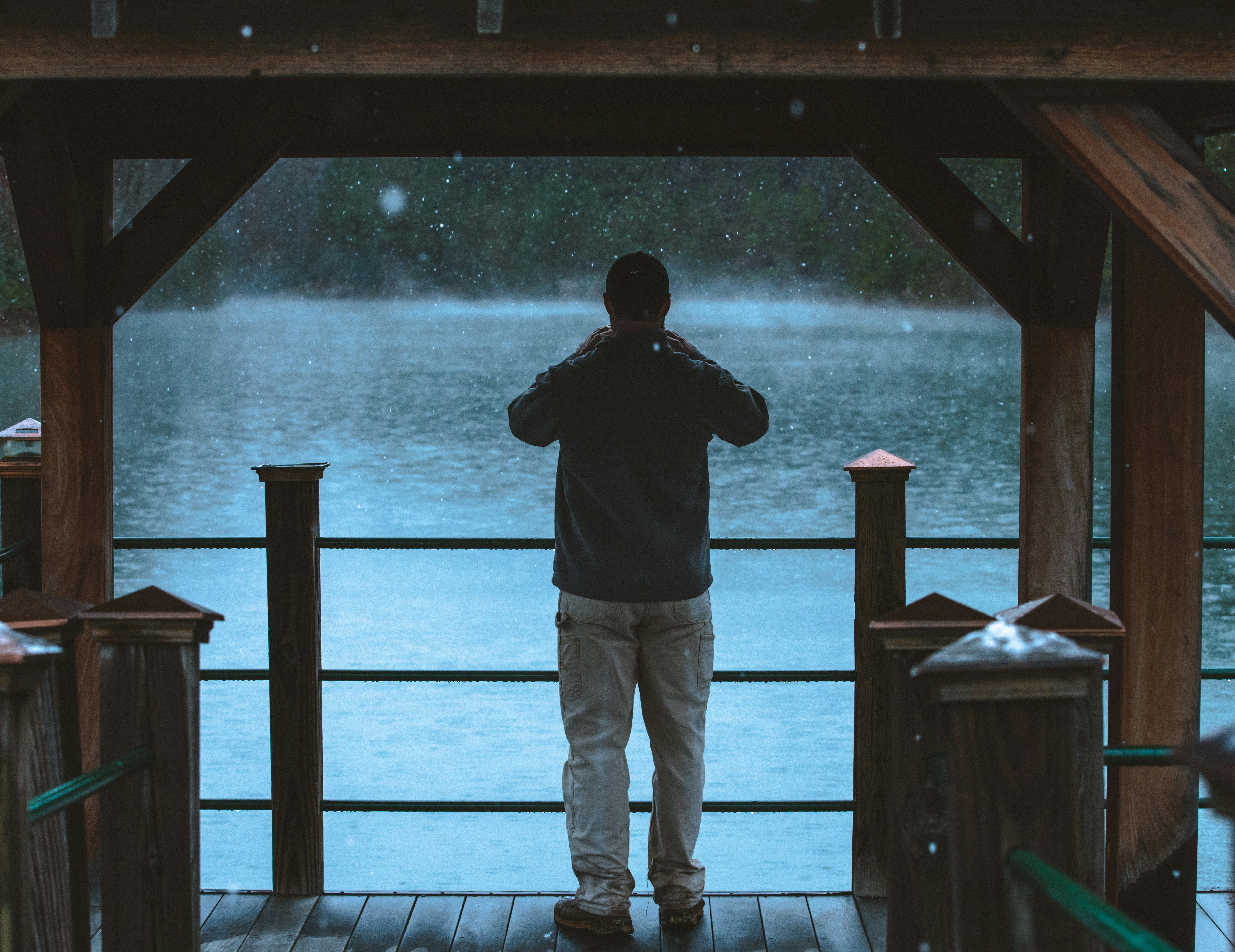 man in black jacket and gray pants standing on brown wooden dock during daytime south carolina teams background