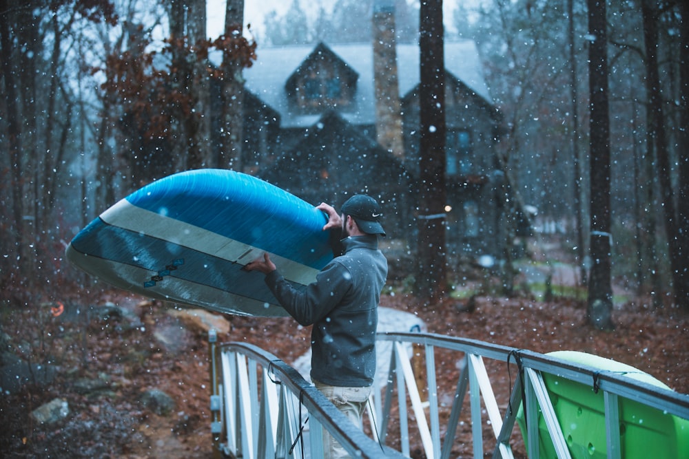 man in black jacket holding blue umbrella