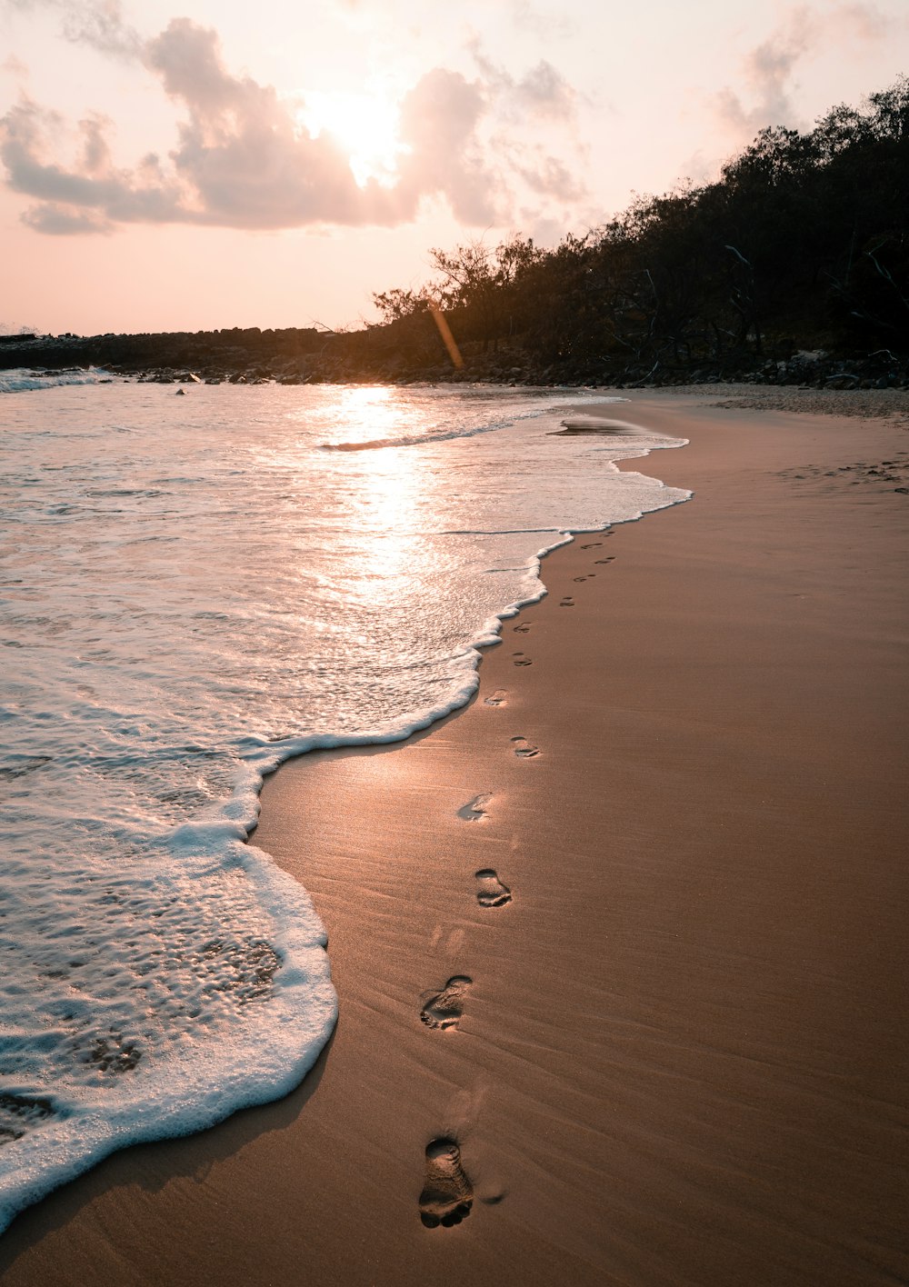 footprints in the sand of a beach at sunset