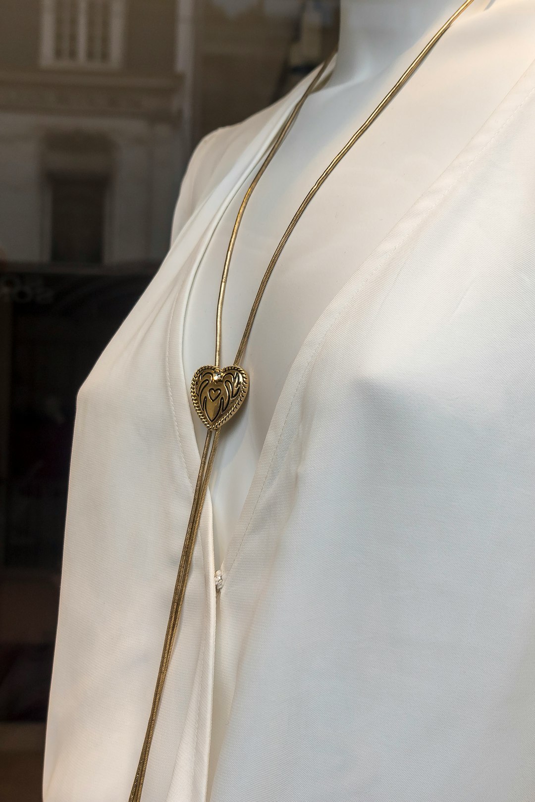 gold round pendant necklace on white textile