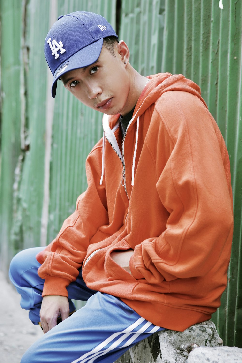 boy in orange hoodie and blue denim jeans sitting on blue plastic stool