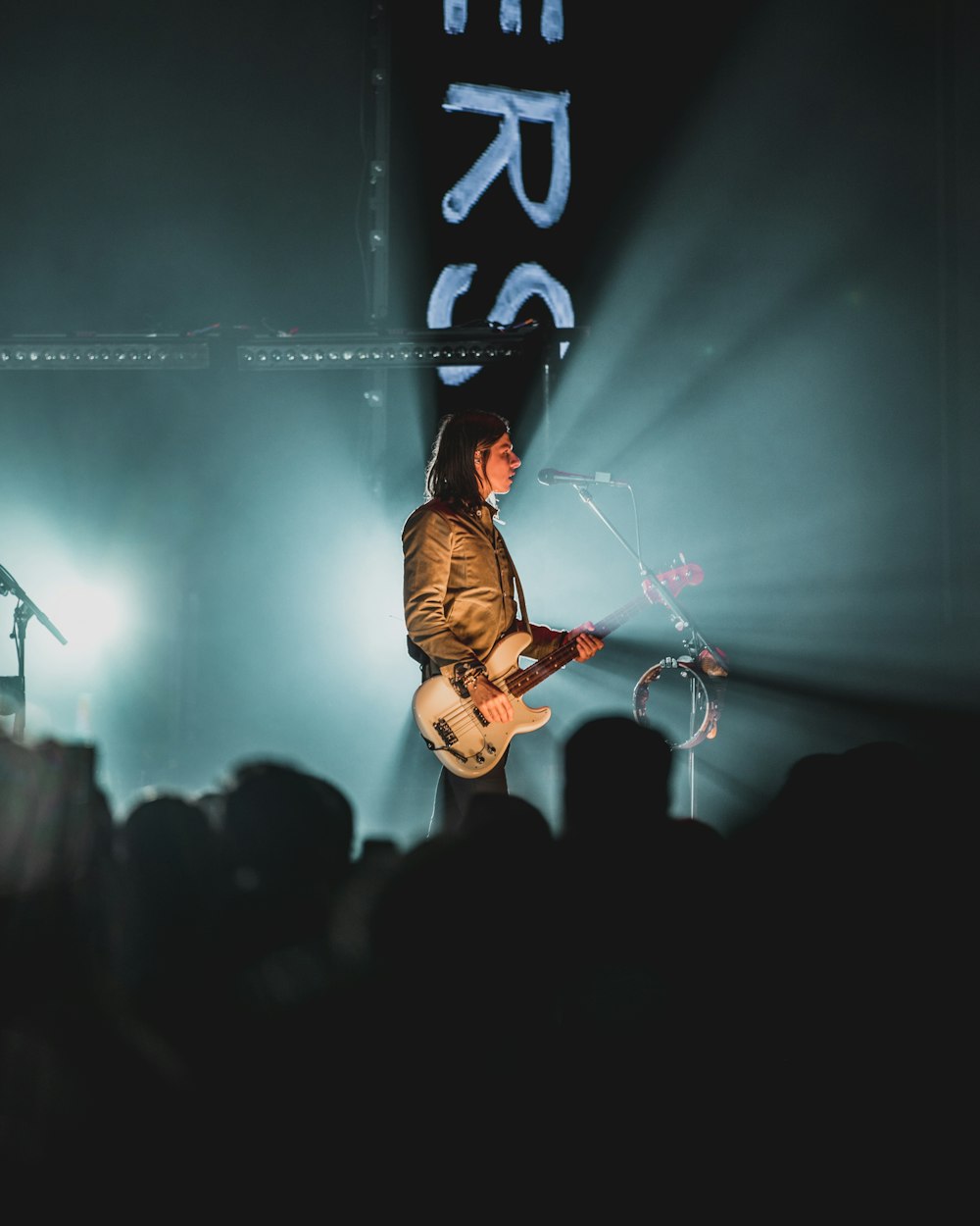 man in black jacket playing guitar on stage