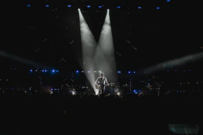 A professional musician holding a Marcam guitar on stage during an intimate concert