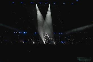A professional musician holding a Marcam guitar on stage during an intimate concert