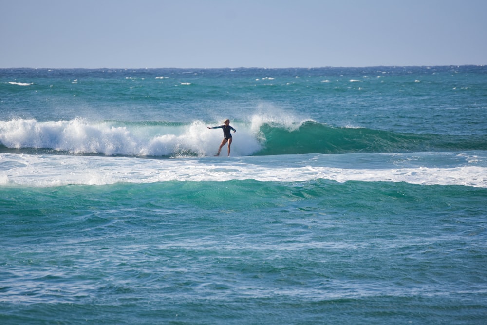 woman surfing on sea waves during daytime