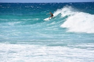 Surfer riding a big wave with clear blue sky overhead.