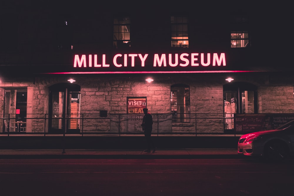 man in black jacket walking on sidewalk during night time