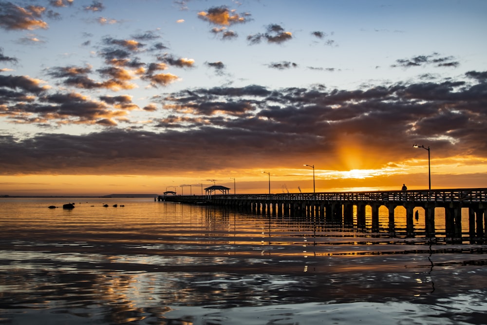 Silueta de la gente en el muelle durante la puesta del sol