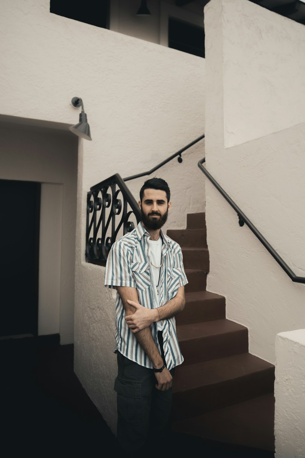 boy in white and blue stripe polo shirt standing on staircase