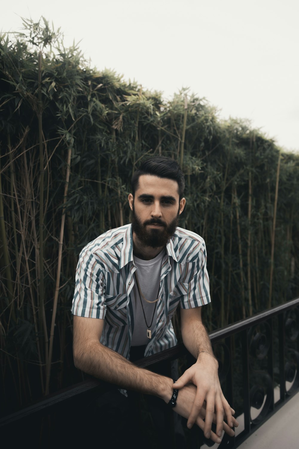 man in white and black stripe polo shirt sitting on black metal railings