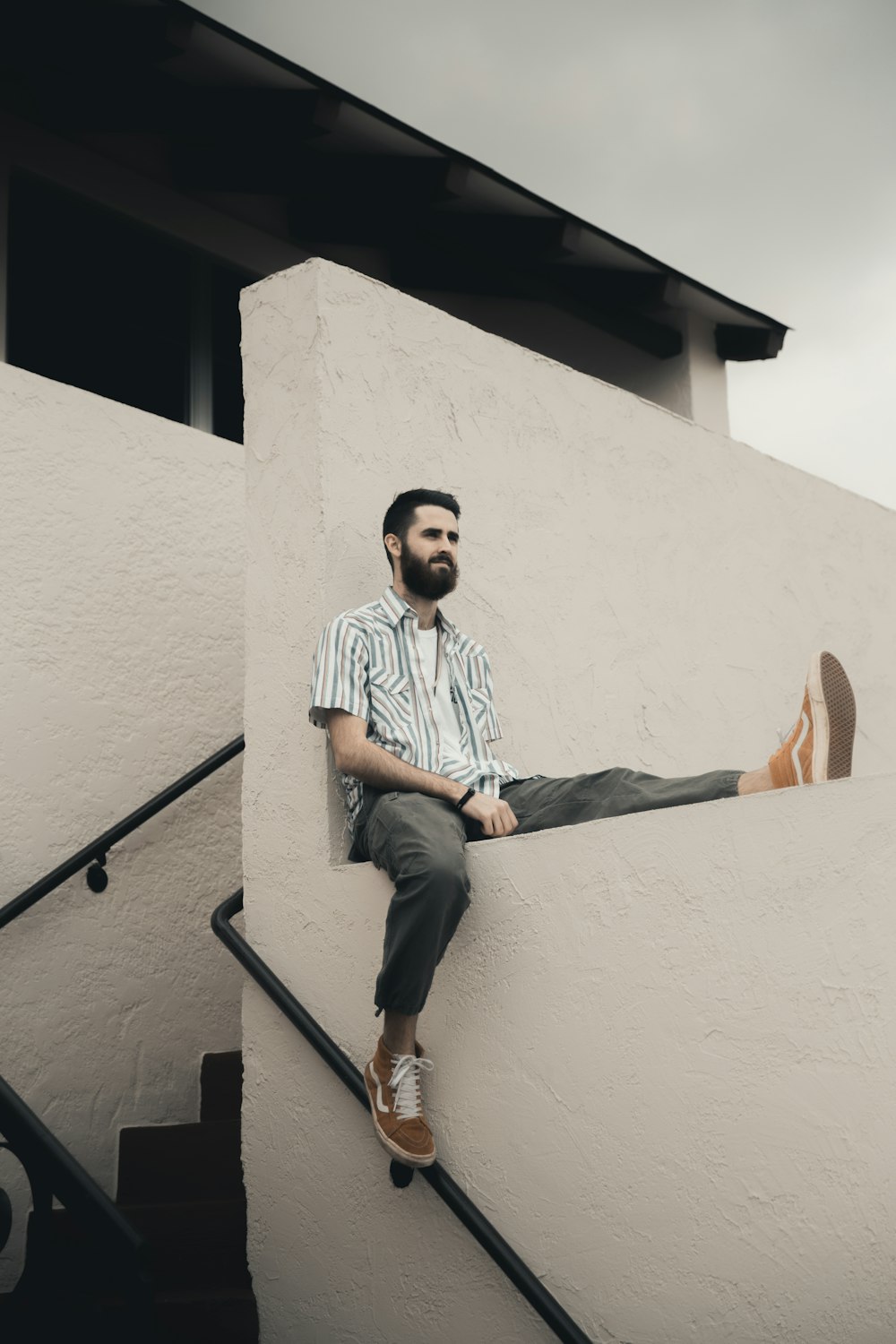 man in blue and white stripe dress shirt and blue denim jeans sitting on concrete staircase