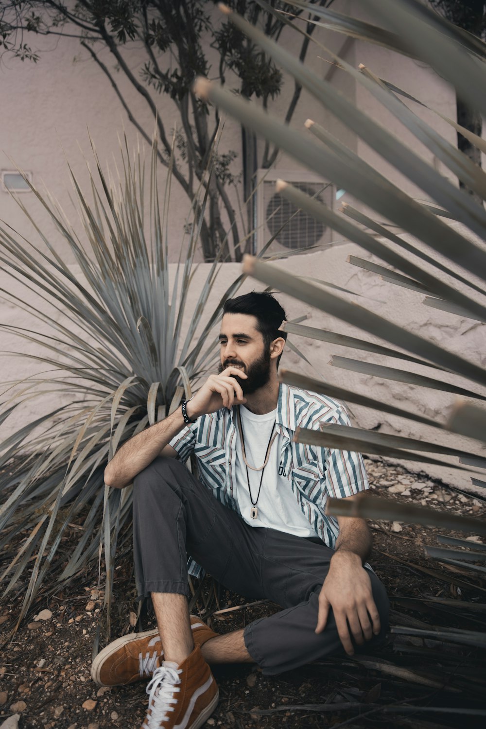 man in white and blue striped button up shirt sitting on brown wooden ladder