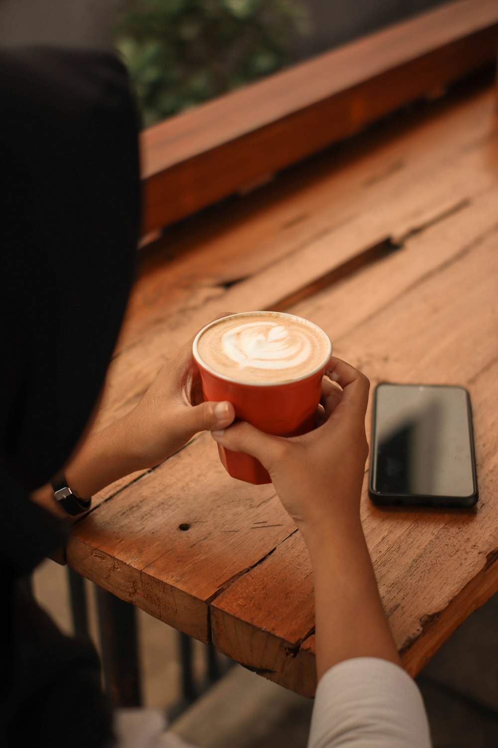 person holding white ceramic mug with brown liquid