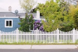 Cozy suburban home with a white picket fence under a bright blue sky.