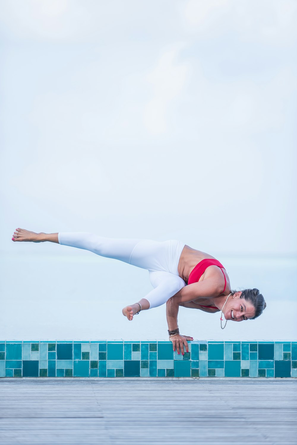 Frau in weißem Tanktop und weißer Hose beim Yoga