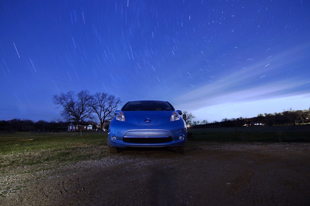 blue car parked on green grass field under blue sky during daytime