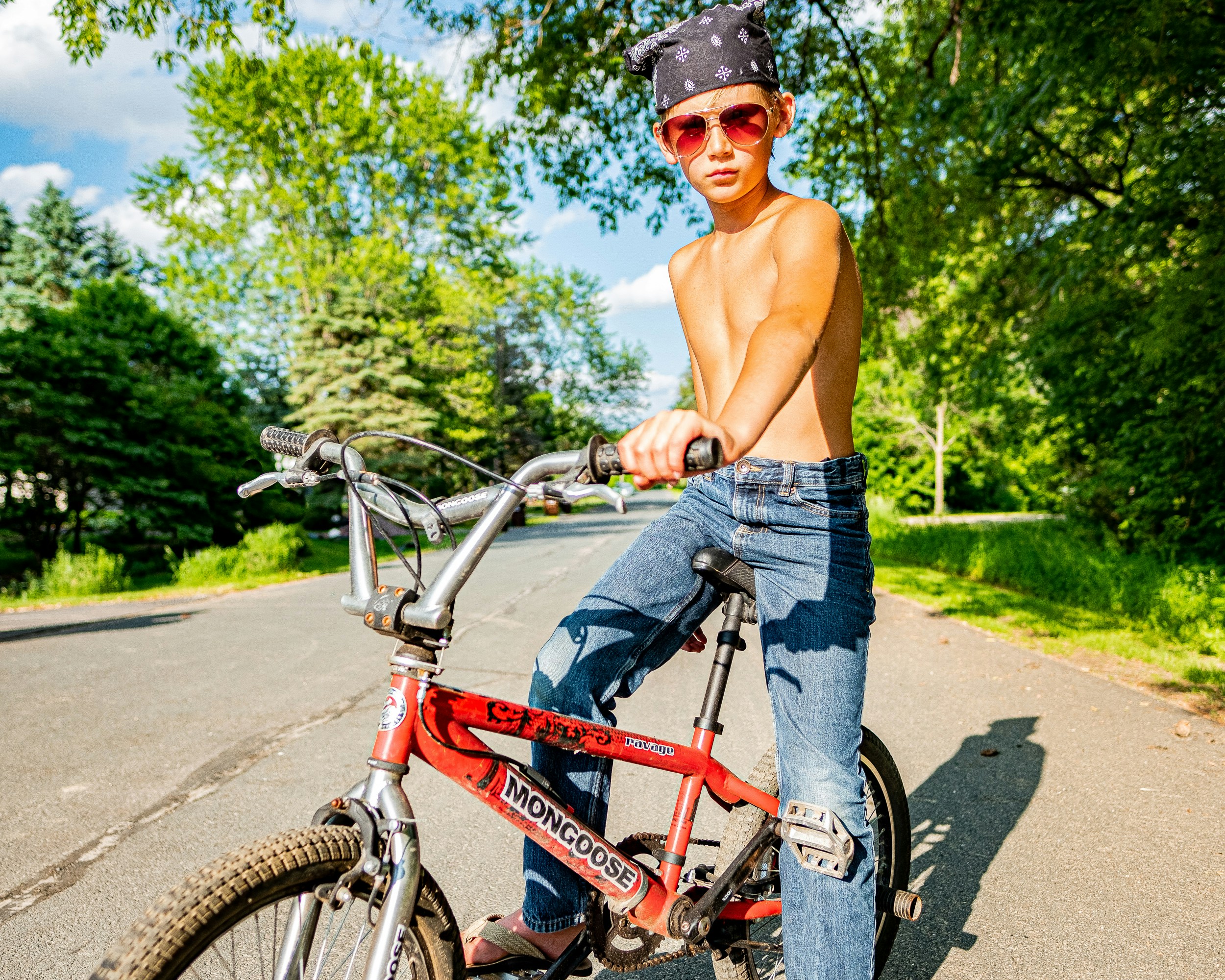 Chico en topless en jeans de mezclilla azul montando bicicleta roja durante el día