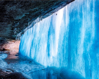 brown and white cave near body of water during daytime icy teams background