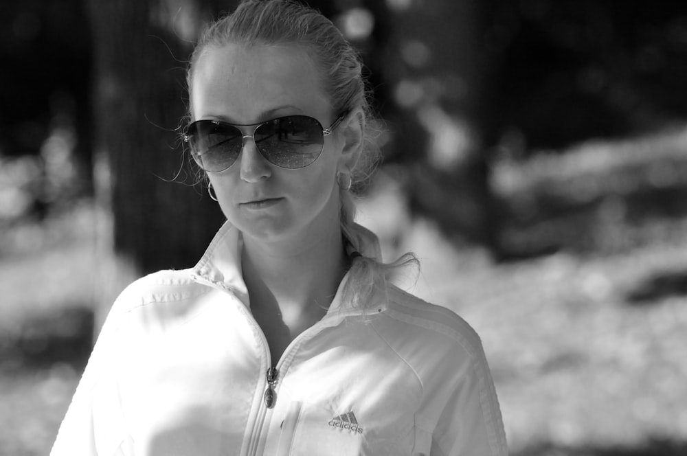 Foto en escala de grises de una mujer con gafas de sol y camisa abotonada