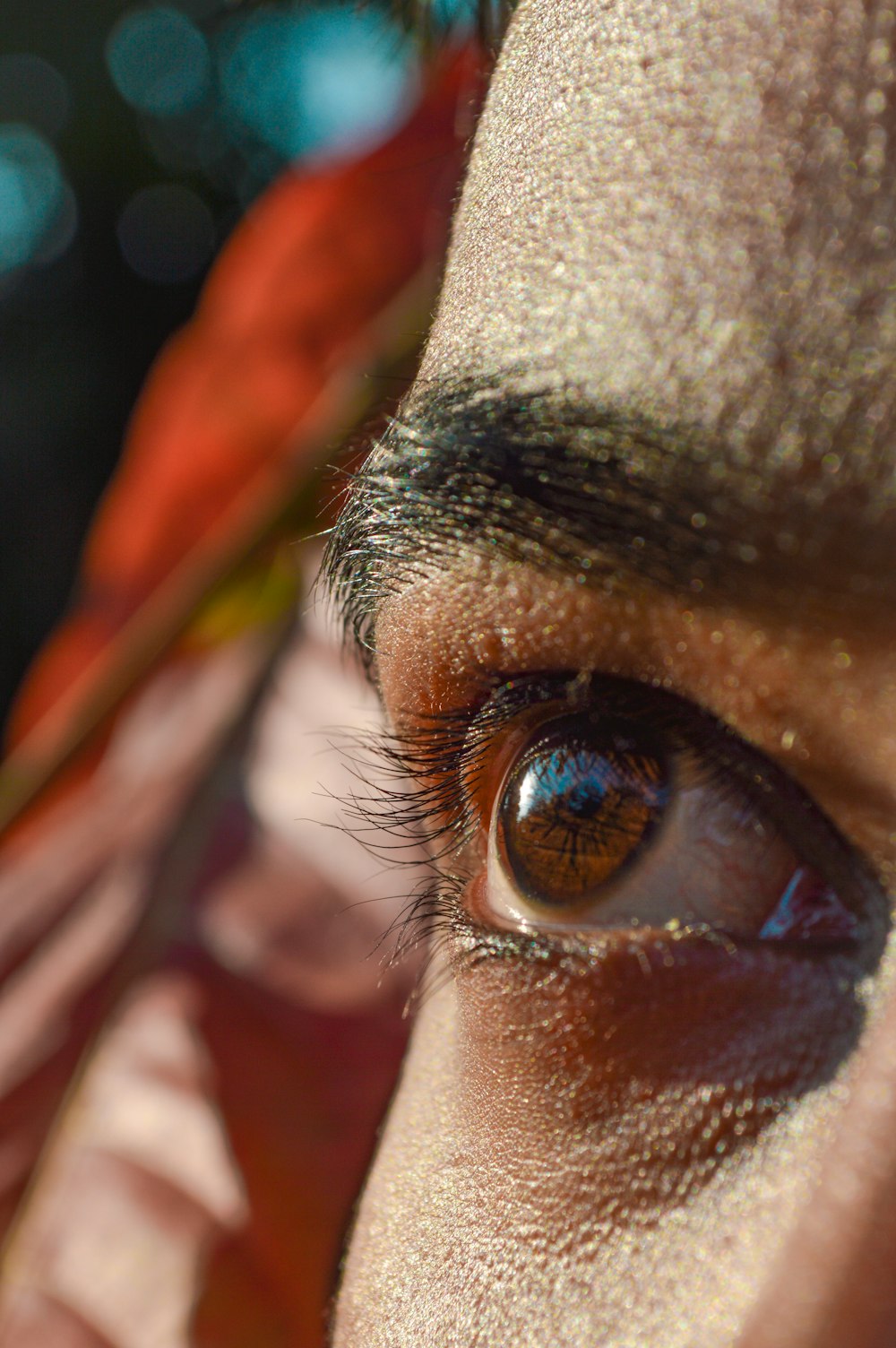 persons eye with orange and yellow feather