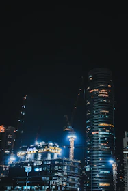 Modern building under construction with futuristic cranes and lights.