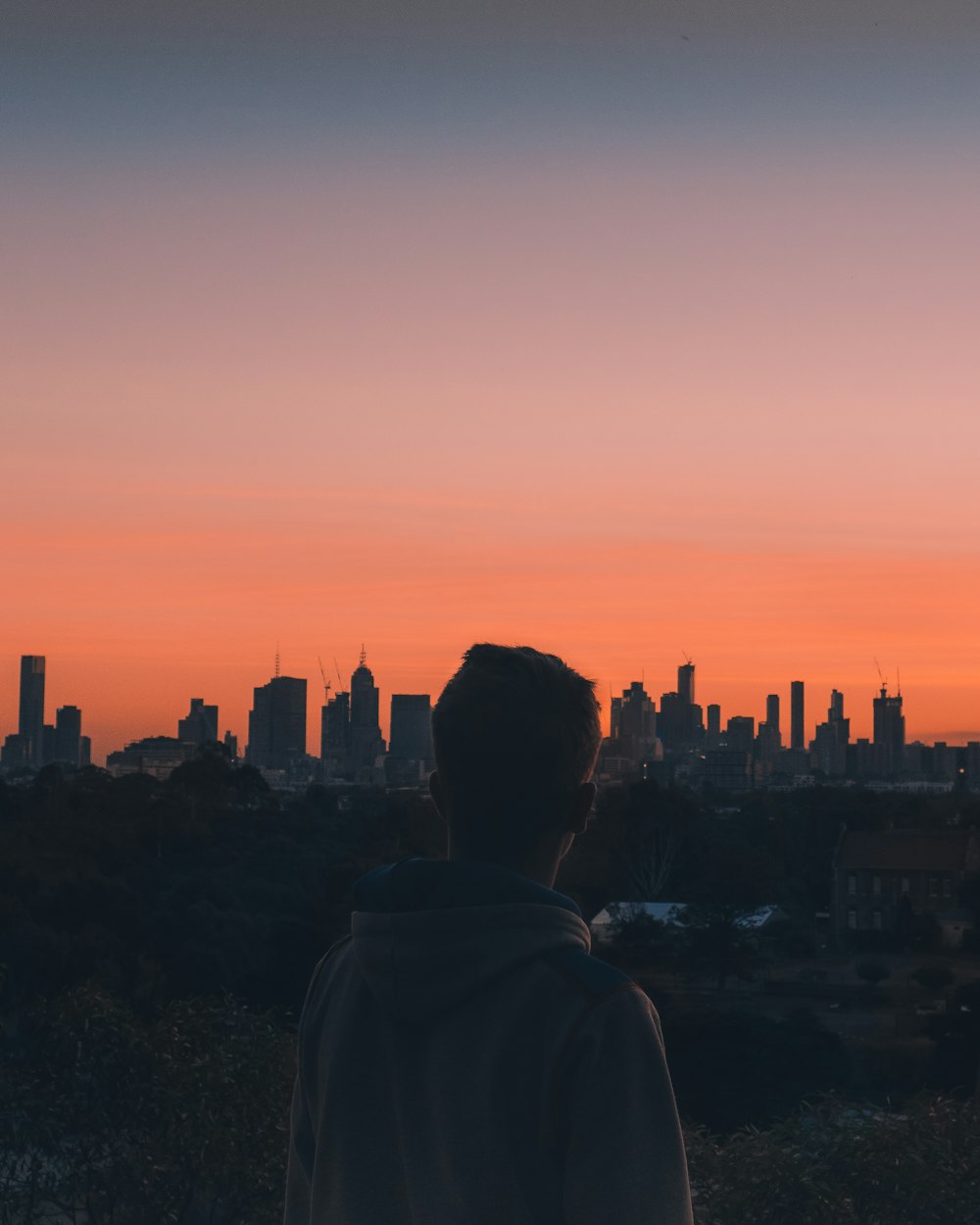 silhouette of man and woman standing on rock formation during sunset