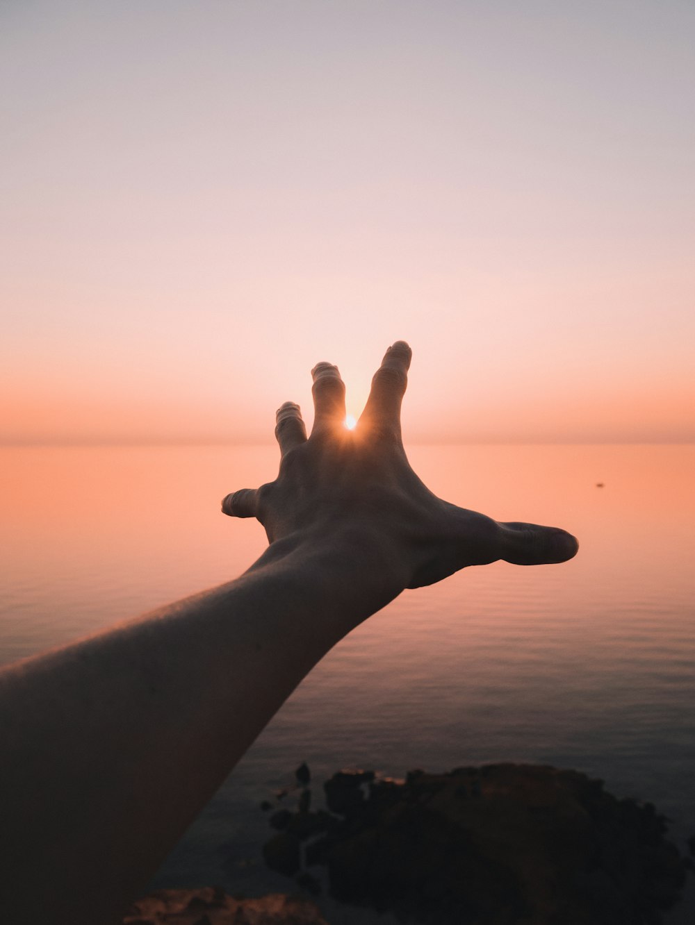 persons left hand with sun setting over the horizon