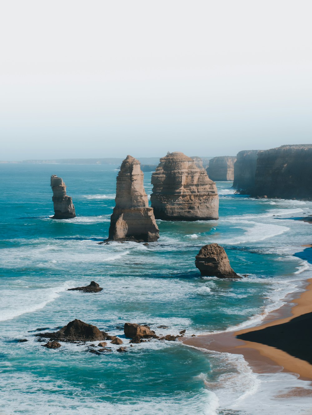 formação rochosa marrom no mar durante o dia