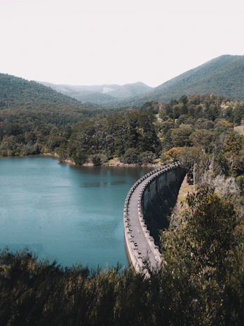 A panoramic view of a completed dam nestled in a lush valley, showcasing structural details.