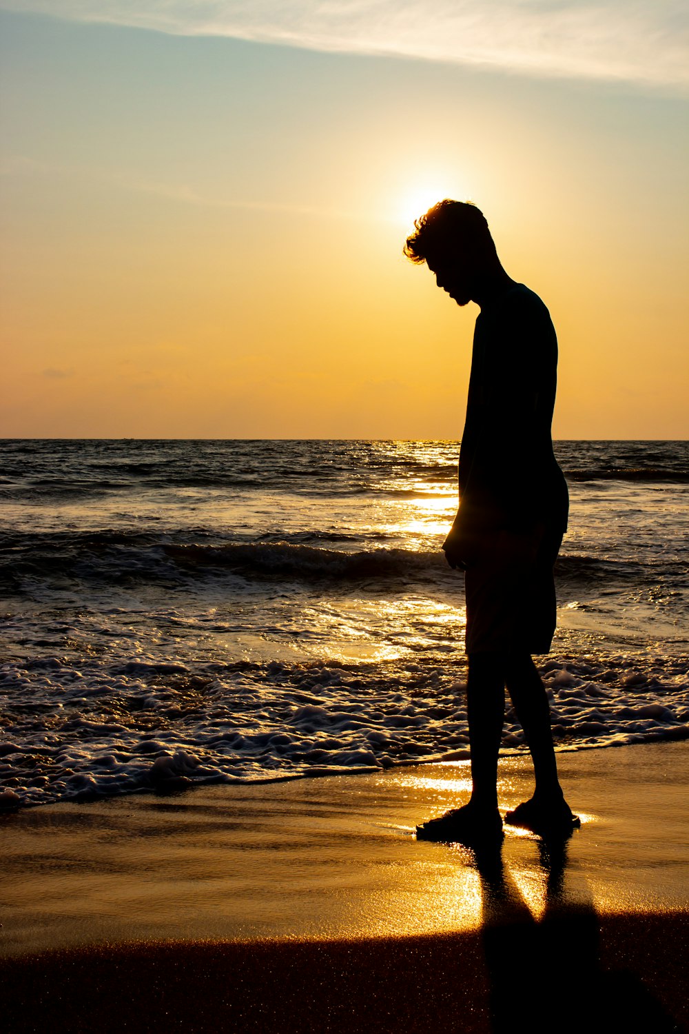 silhouette of woman standing on beach during sunset