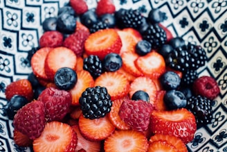 Close-up of ripe strawberries and blueberries in a bowl.