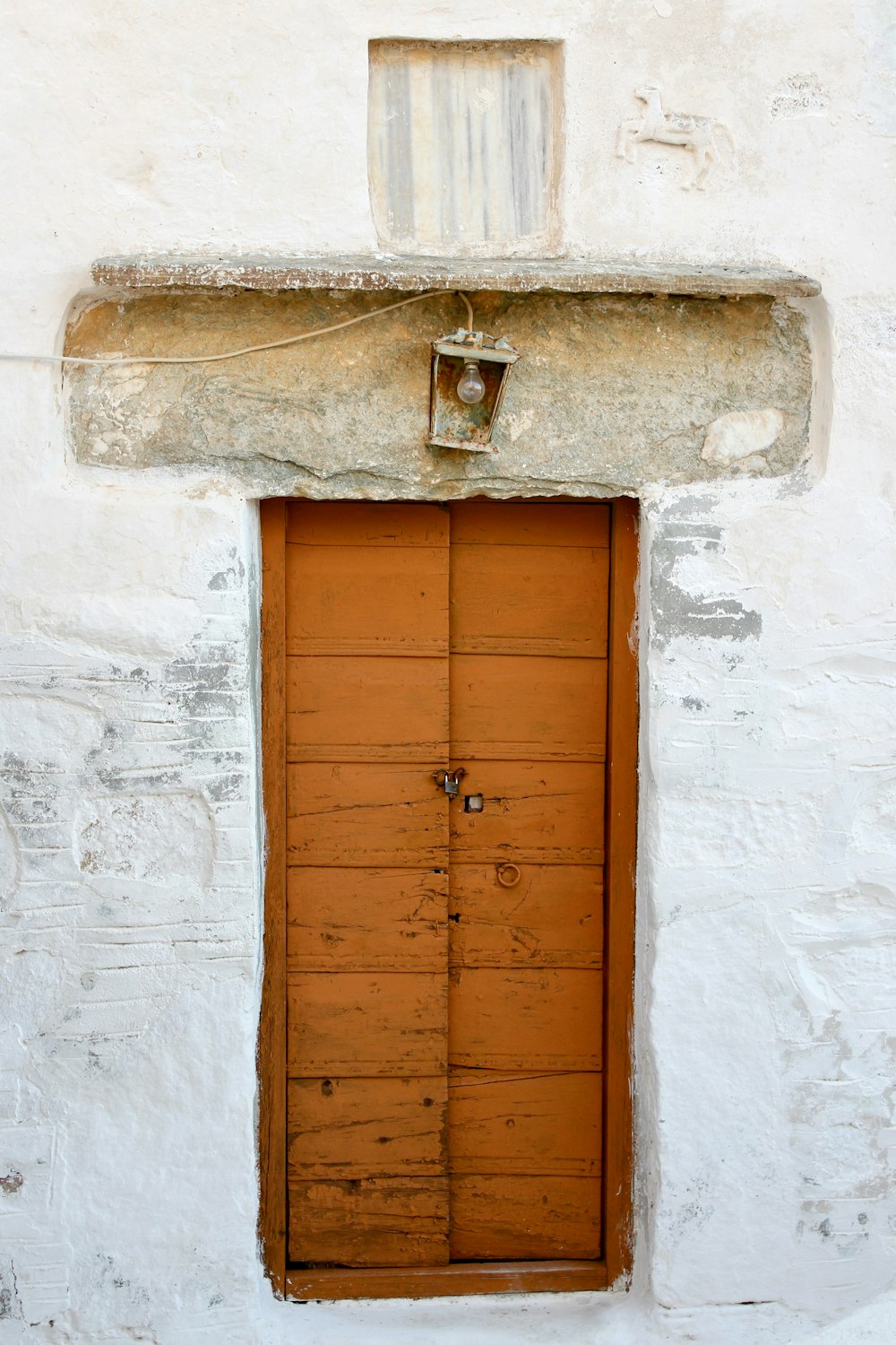 puerta de madera marrón sobre pared de hormigón blanco