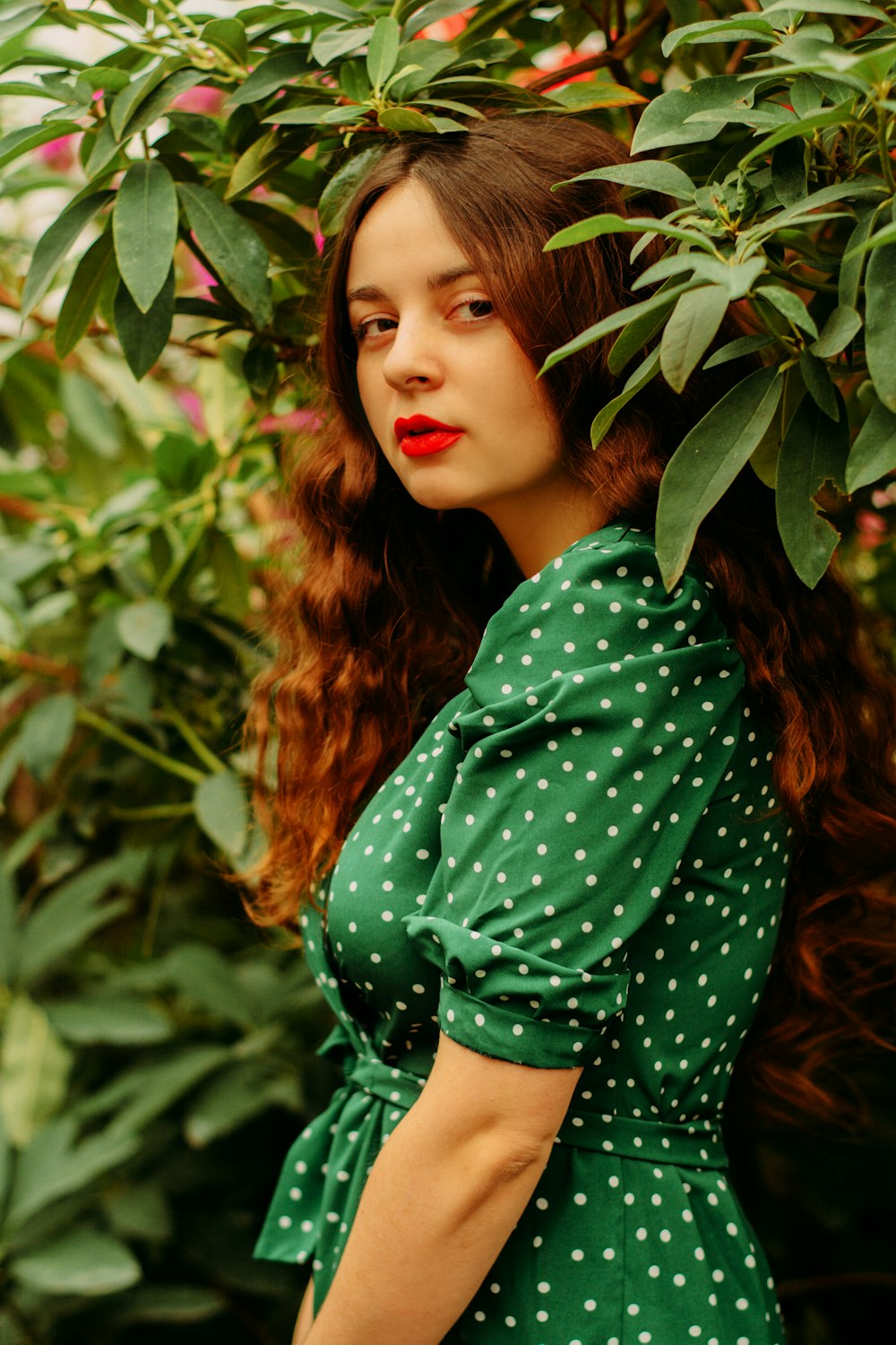 woman in green and black polka dot long sleeve shirt standing beside green plant during daytime