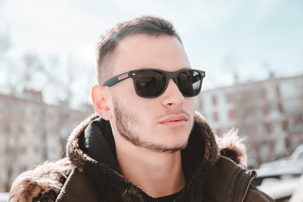 man in black sunglasses and brown coat