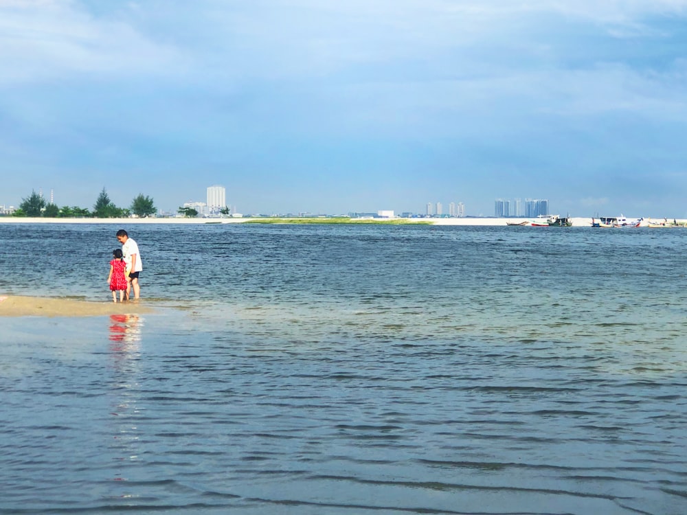 man in white shirt and red shorts standing on sea shore during daytime