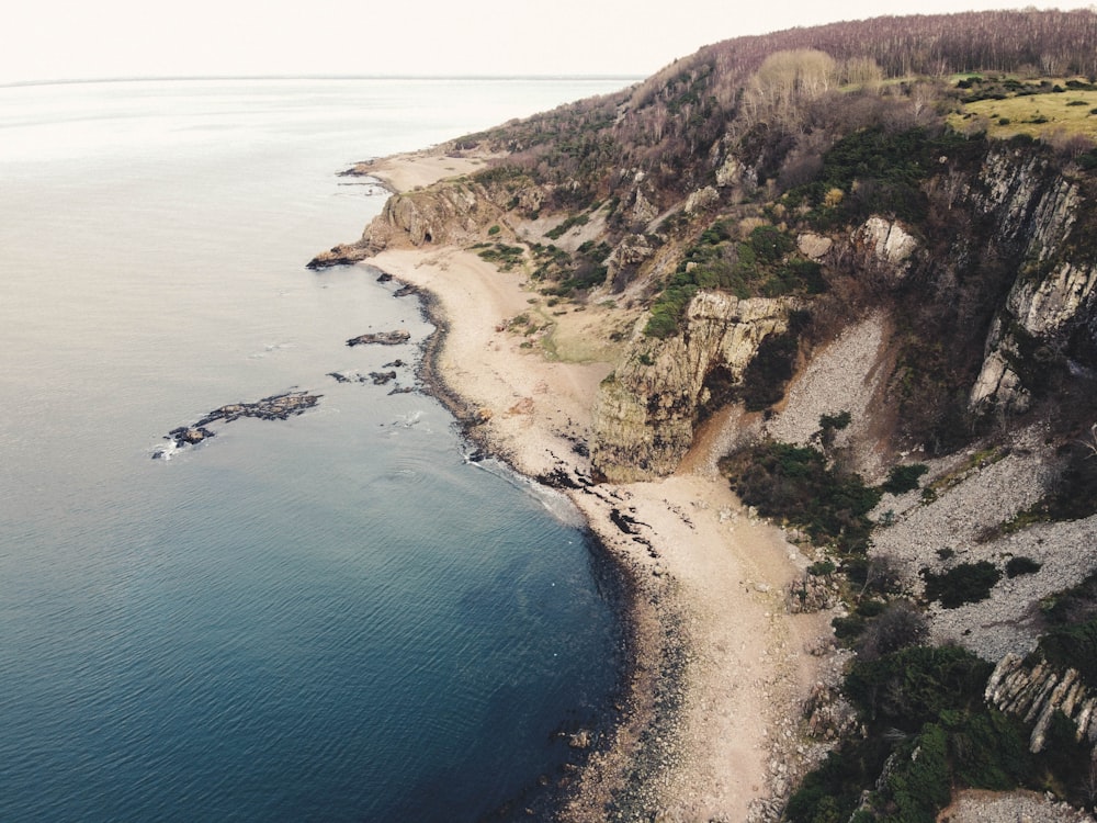 aerial view of green and brown mountain beside blue sea during daytime