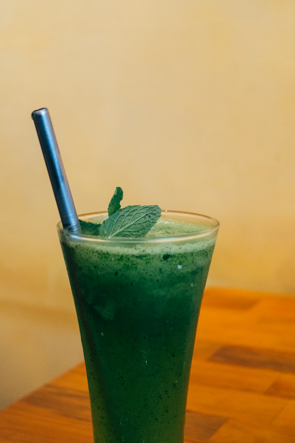 clear drinking glass with green liquid and straw