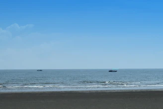 Crystal-clear waves gently lapping against a serene beach with colorful boats anchored nearby.