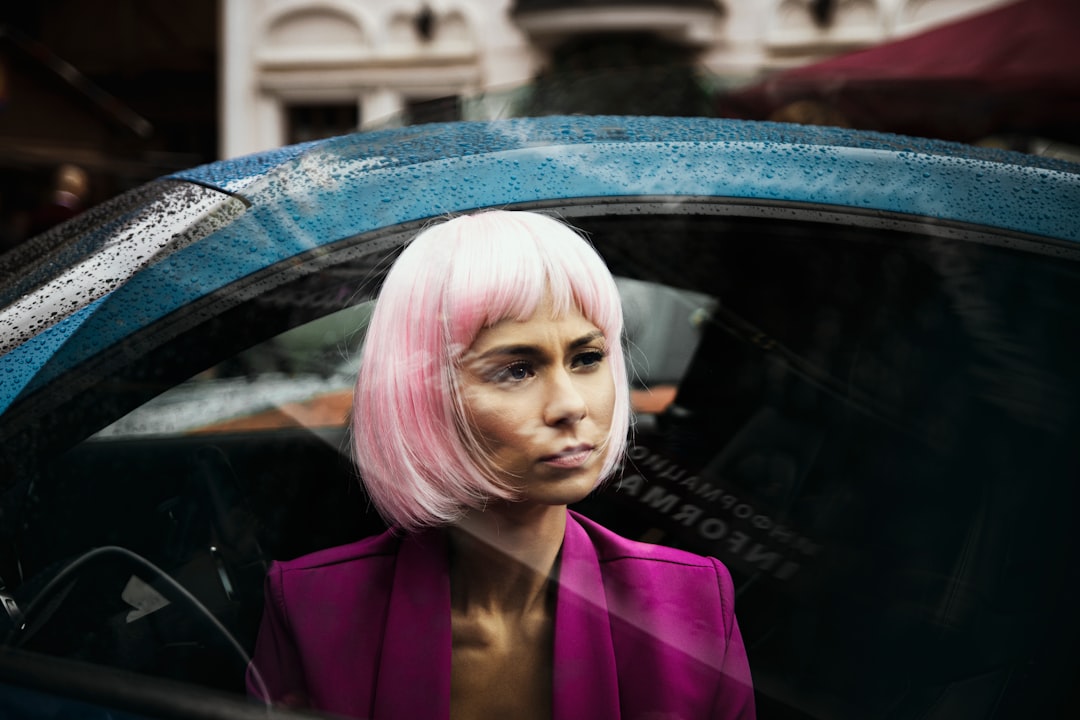 woman in purple blazer standing beside blue car