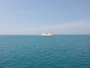A scenic ferry crossing a calm sea under a bright blue sky.