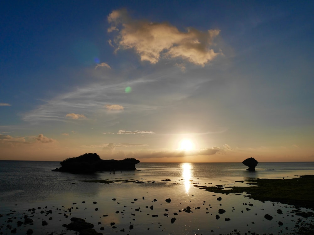 silhouette of rock formation on sea during sunset