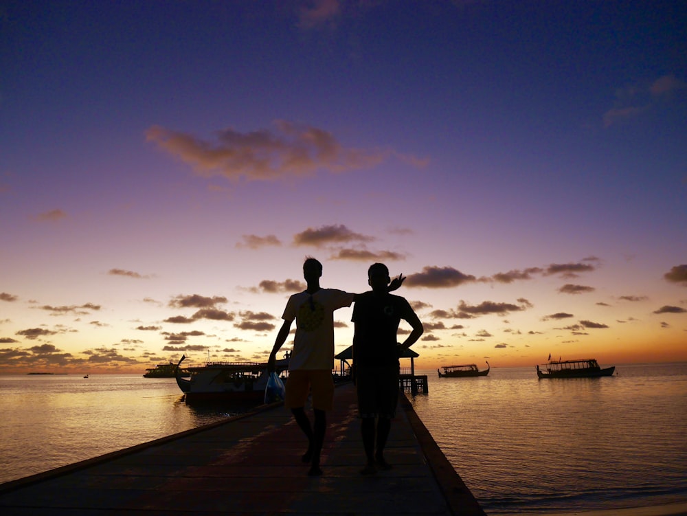 couple standing on wooden dock during sunset