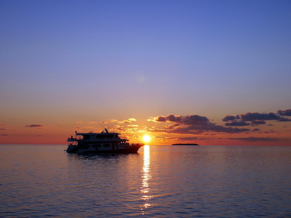 white boat on sea during sunset