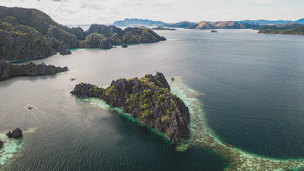 brown and green rock formation on body of water during daytime