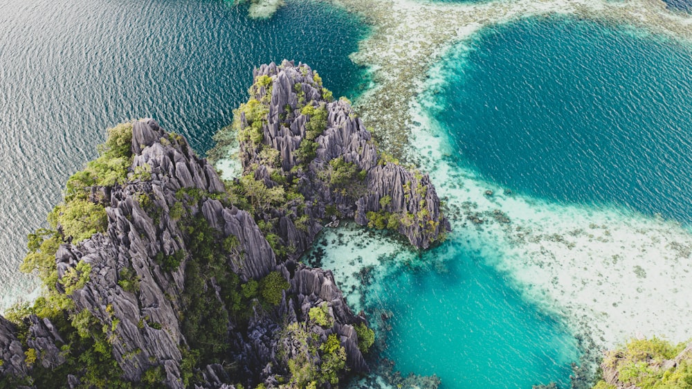 昼間の青い海のそばの緑と茶色の岩層