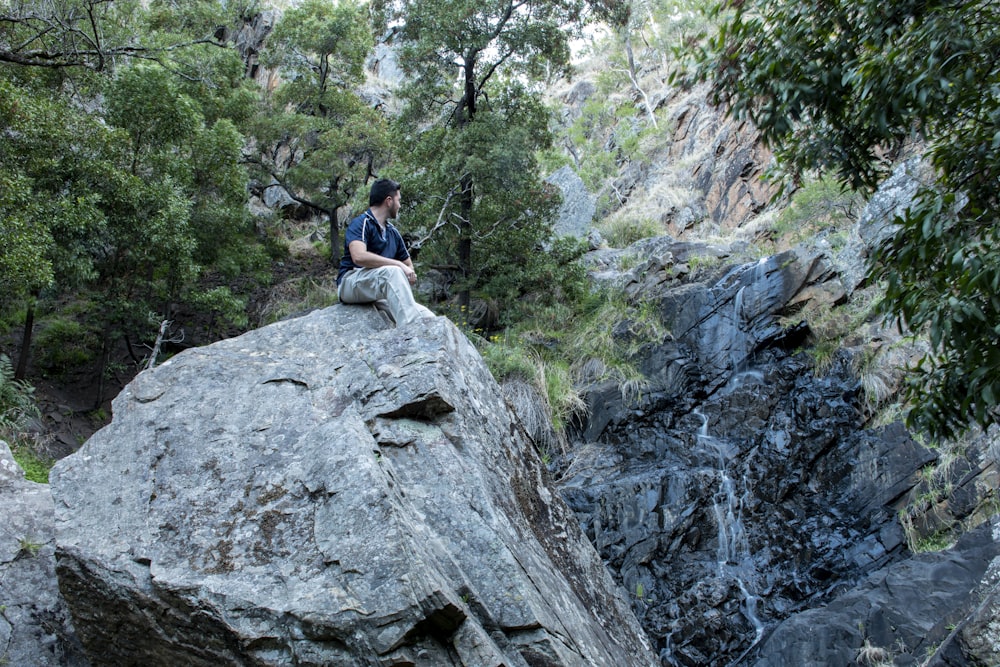 woman in blue shirt sitting on rock during daytime